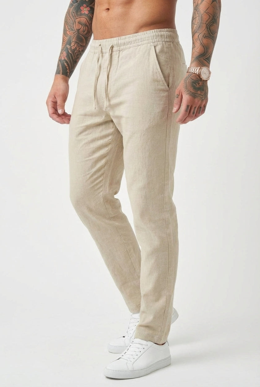 Beige relaxed linen trousers by FJØRNA, featuring a loose fit and lightweight fabric, displayed on a model.