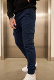 Navy cargo jogger trousers by FJØRNA, featuring a relaxed fit, multiple pockets, and elastic cuffs, styled on a model.