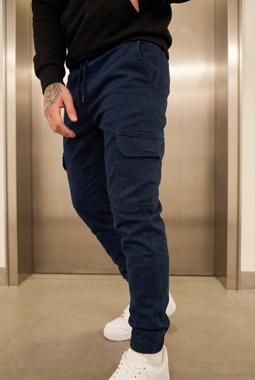 Navy cargo jogger trousers by FJØRNA, featuring a relaxed fit, multiple pockets, and elastic cuffs, styled on a model.