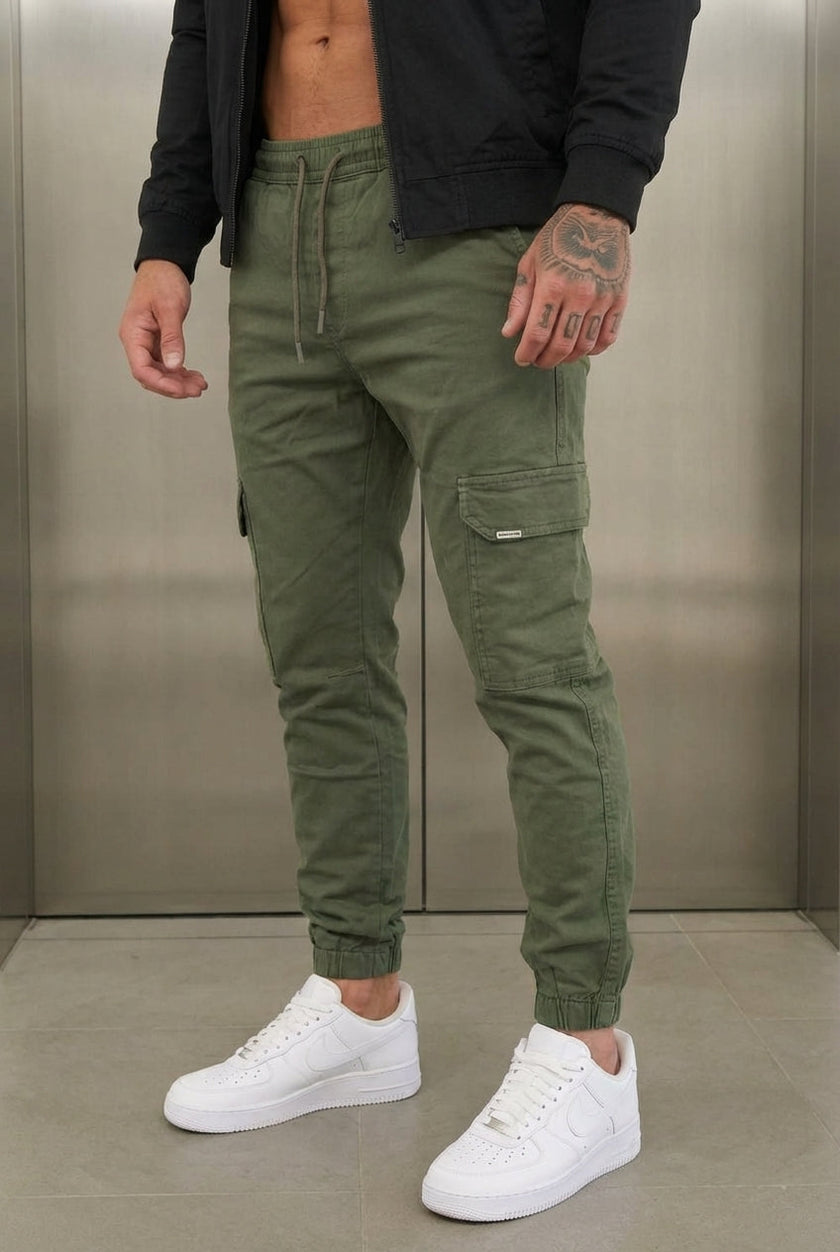 FJØRNA cargo jogger trousers in Army Green, featuring relaxed fit and multiple pockets, shown on a model.