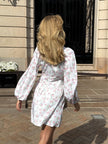 FJØRNA white floral V-neck mini dress with lantern sleeves, back view showcasing lightweight fabric and elegant design.
