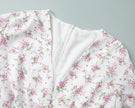 FJØRNA white floral mini dress with V-neckline and lantern sleeves, showcasing intricate floral pattern and elegant design.