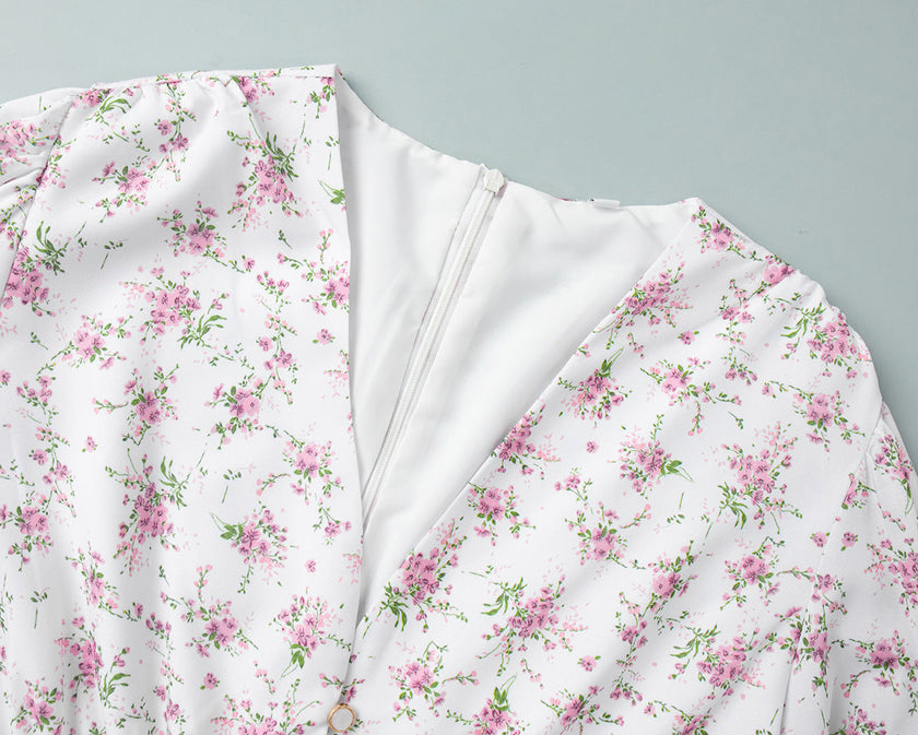 FJØRNA white floral mini dress with V-neckline and lantern sleeves, showcasing intricate floral pattern and elegant design.