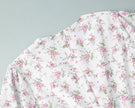 FJØRNA white V-neck floral mini dress with lantern sleeves, detailed close-up of fabric and design.