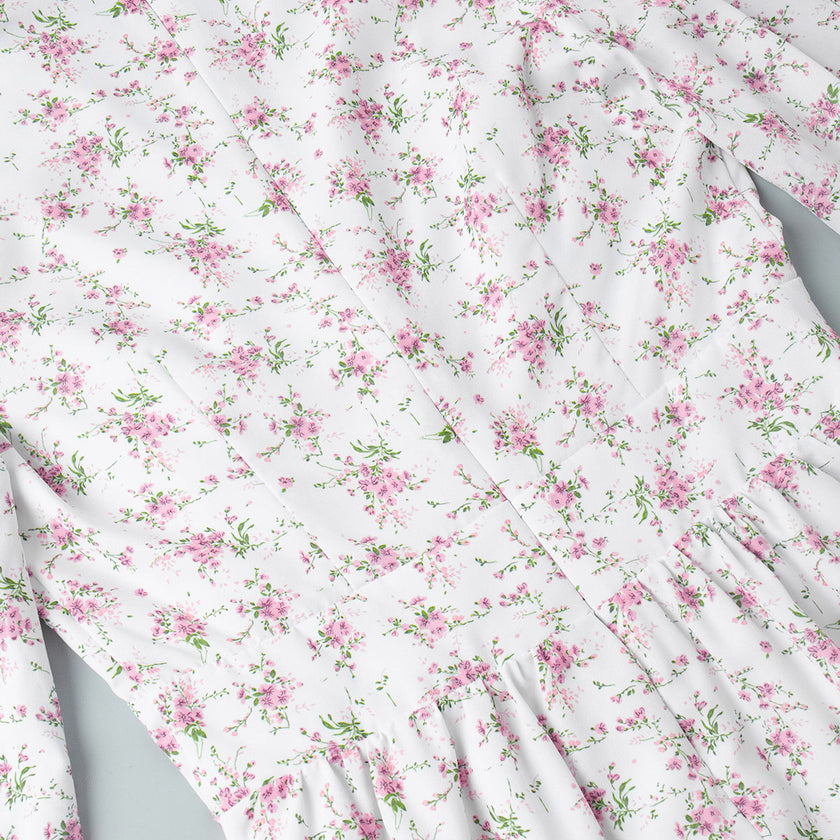 FJØRNA V-neck white floral mini dress with lantern sleeves, detailed view of the elegant floral pattern and lightweight fabric.