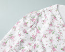 FJØRNA white v-neck floral mini dress with lantern sleeves, showcasing a detailed view of the elegant flower pattern.