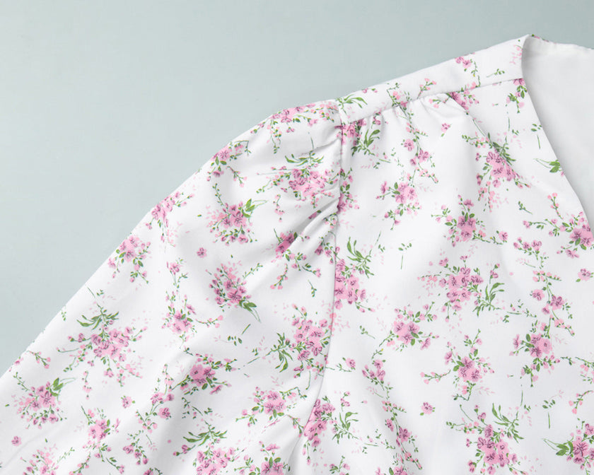 FJØRNA white v-neck floral mini dress with lantern sleeves, showcasing a detailed view of the elegant flower pattern.