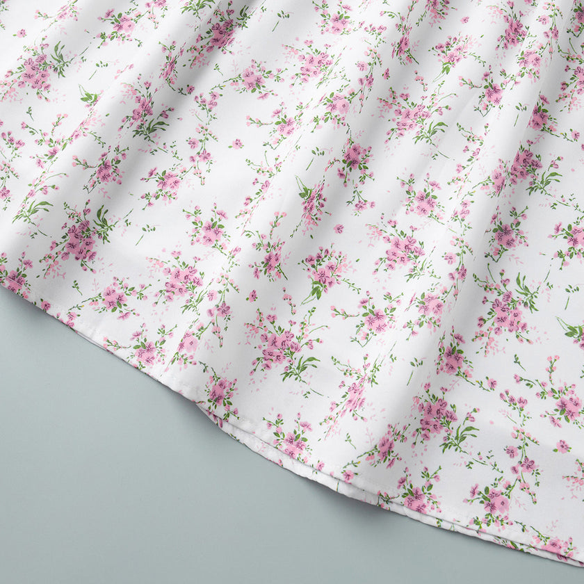 FJØRNA white floral V-neck mini dress with lantern sleeves, detailed view of the elegant floral pattern and feminine design.