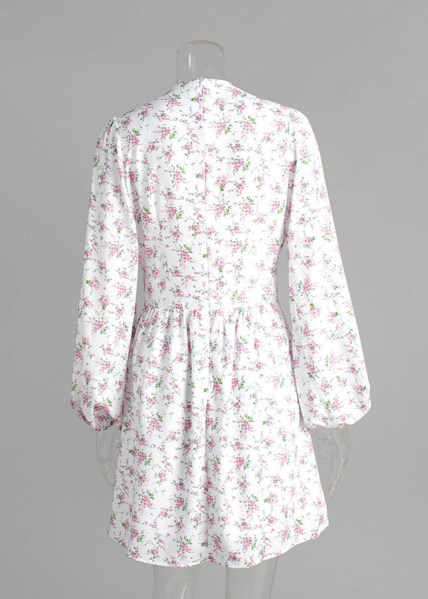 FJØRNA V-neck white floral mini dress with lantern sleeves, shown from the back, perfect for spring and summer occasions.