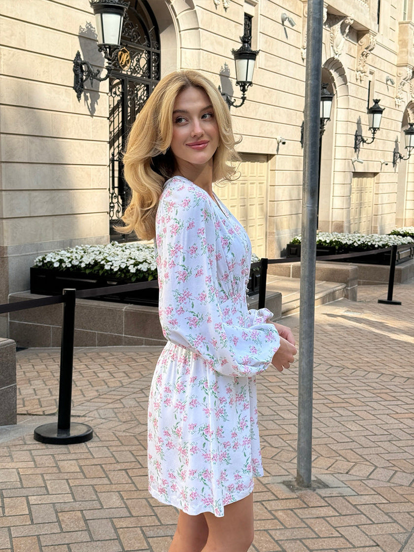 FJØRNA V-neck white floral mini dress with lantern sleeves, shown from the side, showcasing the lightweight fabric and elegant design.