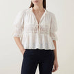 White women's summer blouse with V-neck, puff sleeves, and lace details by FJØRNA, perfect for warm-weather outfits.
