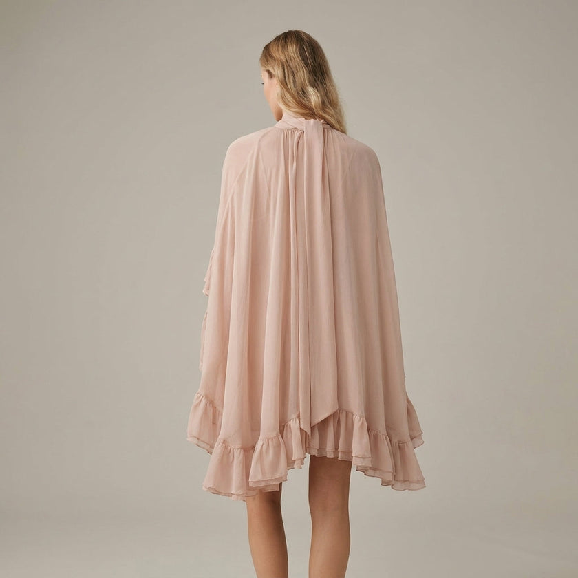 FJØRNA ruffle chiffon mini dress with high neck and layered fit, shown from the back in salmon color.